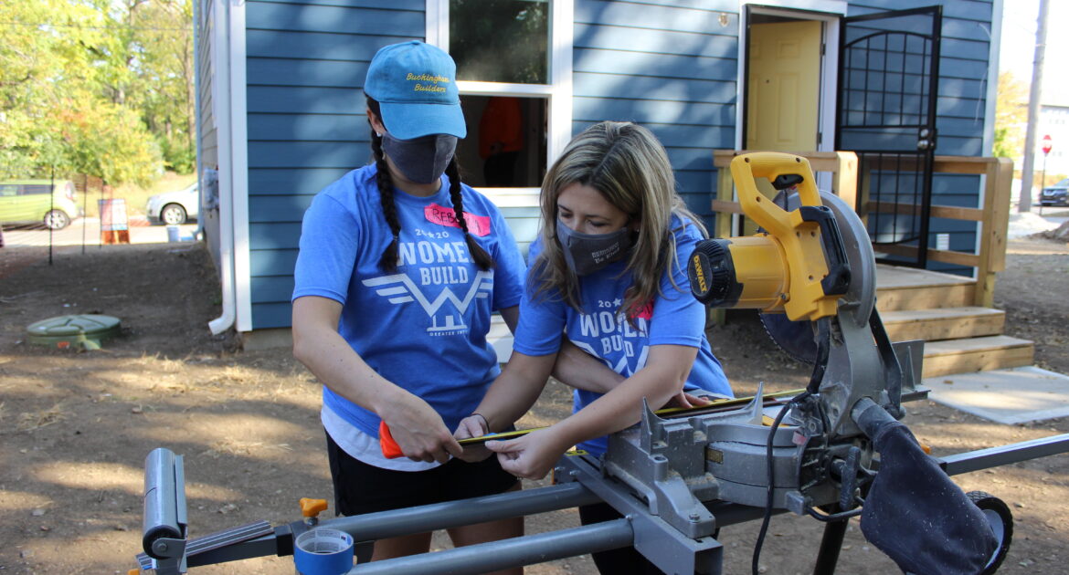 Two women using saw during a volunteer event.